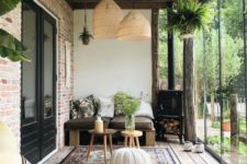 a boho screened porch with pallet furniture, pillows, wicker lamps, boho rugs and a crochet ottoman