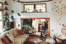 a boho space with boho rugs and pillows, branch hangings, a mirror, a glass coffee table and potted plants