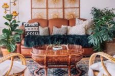 a bright Moroccan living room with a rust leather sofa, rattan chairs, potted plants and Moroccan lamps