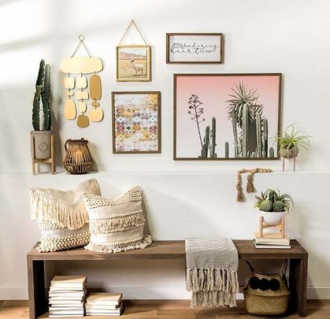a bright boho hallway with a wooden bench, boho fringe pillows, a baket for storage and a gallery wall with artworks, hangings and potted plants