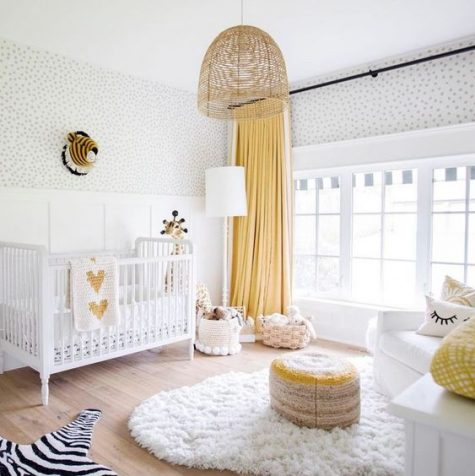 a bright nursery in white and yellow, with a fluffy rug, a colorful ottoman and baskets for storage