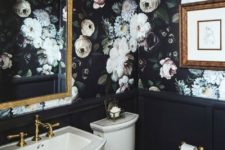a chic powder room done with moody realistic floral wallpaper and black wainscoting