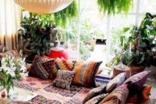 a colorful gypsy living room with a conversation zone, boho pillows and blankets, potted greenery and a lamp