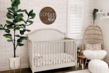 a cozy neutral modern nursery with wallpaper walls, a sign, wicker chairs and a lampshade, potted greenery