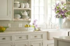 a farmhouse kitchen done in white and aqua, with vintage cabinets and stone countertops and blooms