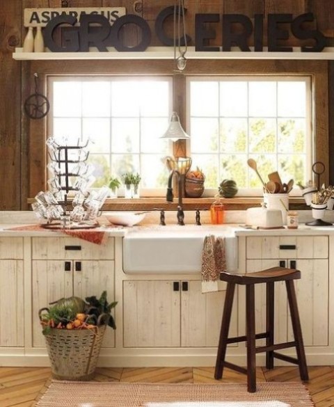 a farmhouse kitchen with stained wooden walls, white cabinets, a wooden stool and some pretty decor in vintage style