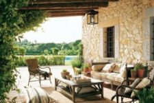 a farmhouse patio with wooden and rattan furniture, comfy upholkstery, rugs and cushions