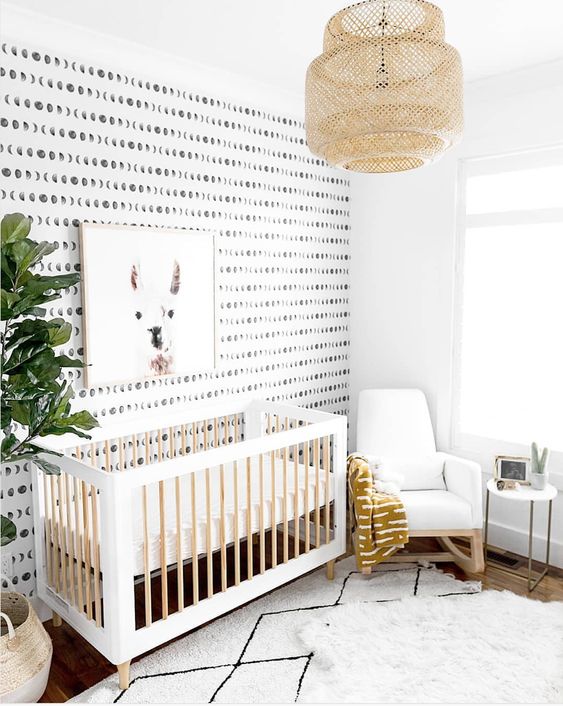 a gender neutral nursery with a printed wall, a printed rug, a woven lamp, a potted tree and an artwork