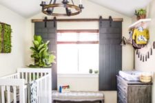 a gorgeous rustic nursery with sliding shutters, a wooden chandelier, a weathered dresser and prints