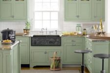 a green farmhouse kitchen with vintage cabinets and butcherblock countertops, metal stools and touches of metal
