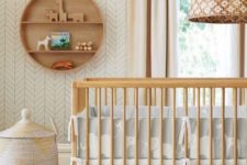 a mid-century modern nursery in done neutrals, with wooden furniture, a basket and a round shelf