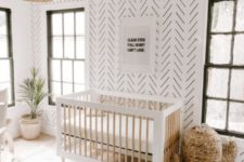 a minimal boho nursery with wallpaper walls, a wicker cactus for storage, a wicker lampshade and a rug inspired by Moroccan wedding blankets