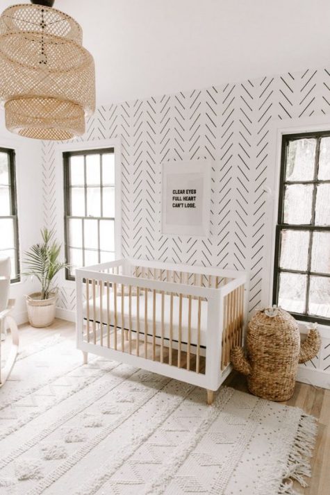 a minimal boho nursery with wallpaper walls, a wicker cactus for storage, a wicker lampshade and a rug inspired by Moroccan wedding blankets