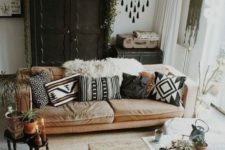 a monochrome boho living space with a wahsed out sofa, black vintage furniture, a pallet wood cofeee table, folksy pillows and tassels