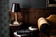 a moody masculine space done with dark textural wallpaper and dark-stained wainscoting for a refined touch