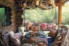 a rustic cabin patio with an antler chandelier, wooden chairs and colorful textiles for a boho feel