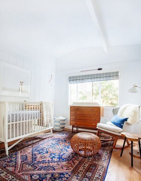 a stylish mid century modern nursery with a large rug, stained wooden furniture, blue shades and a dog artwork
