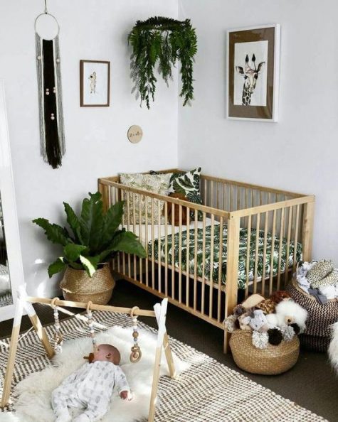 a tropical boho nursery with tropical bedding, baskets for storage, printed rugs, potted greenery