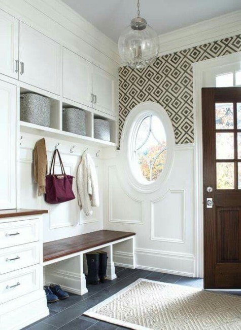 a vintage farmhouse entryway with white wainscoting on the walls and a round window that matches