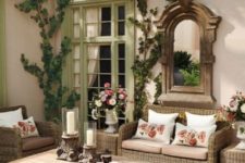 a welcoming rustic patio with wicker and wooden furniture, lot sof vines and a vintage mirror in a wooden frame