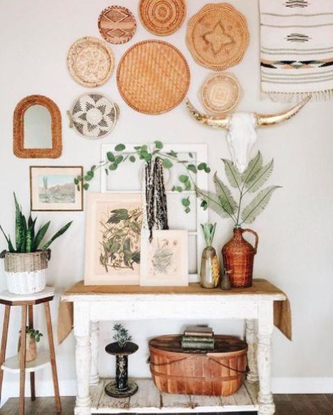 a whimsy boho entryway with decorative plates, a vintage console and potted greenery plus wicker touches