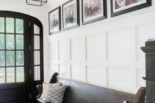 a white ceiling and wainscoting contrast a dark door, floor and furniture and make up a chic space