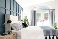an airy and lively bedroom with a navy paneling accent wall that brings a bold and chic statement