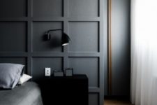 black paneling used as a headboard coming up to the ceiling and to divide the bedroom and the closet