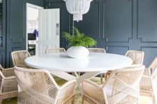 graphite grey paneling, rattan furniture, a white bead chandelier and a printed yellow rug for an eclectic dining room