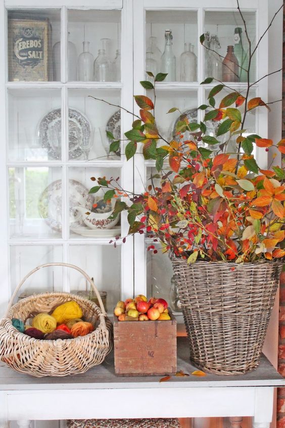 a fall display of baskets with colorful yarn and fall leaves and a crate with fresh apples