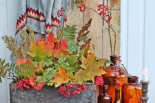 07 a stylish fall display with colorful bottles, candle holders, a concrete box with fall leaves and berries