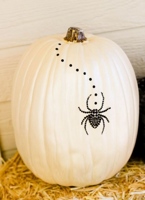 a white pumpkin with black studs and a black spider of them is a creative and cool non-carving pumpkin idea