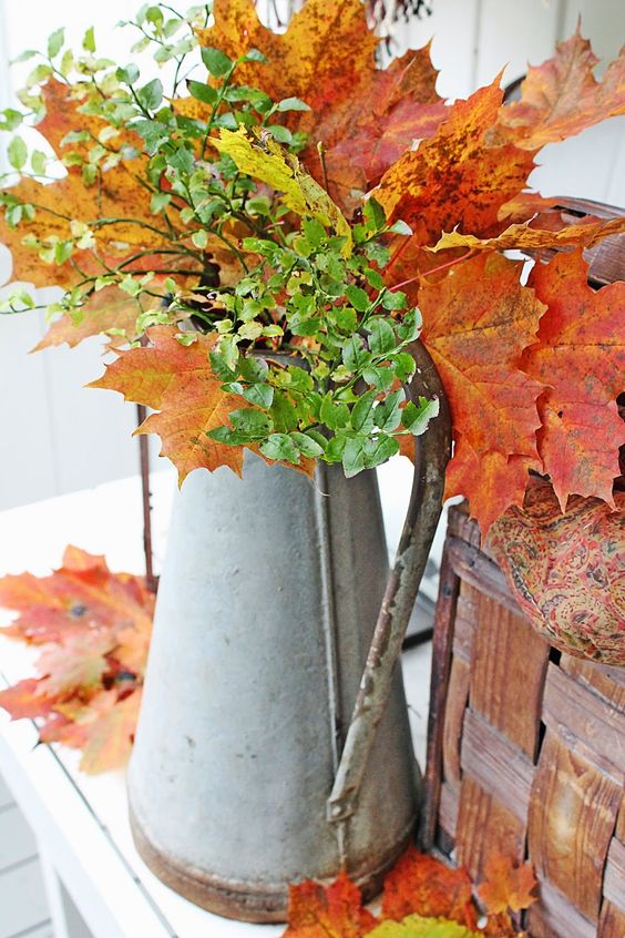 an antique metal jug with fall leaves and greenery for home decor is a great idea for a rustic space