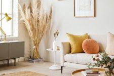 14 a bright and chic fall-inspired space done with orange and yellow touches, with a neutral rug and wheat