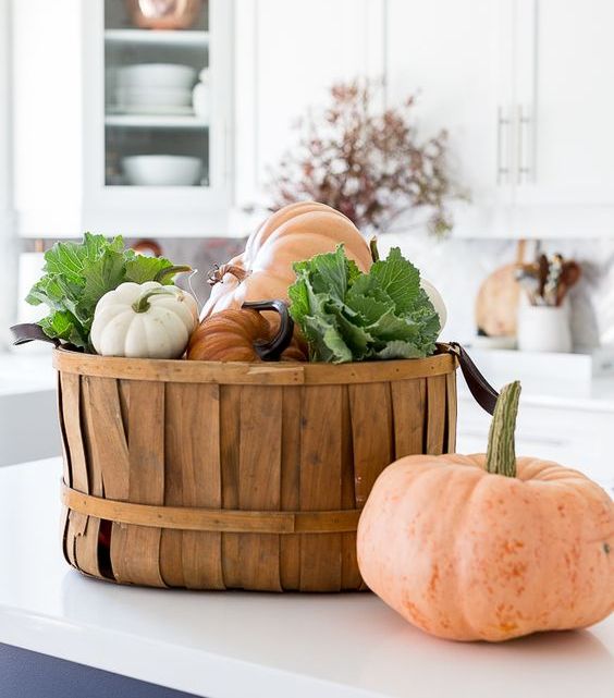 a wooden basket with fresh pumpkins and veggies is a cool and edible fall decoration