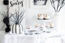 16 a cool Halloween buffet table with ghost cupcakes, a stenciled pumpkin, black branches in a white vase, a couple of cool signs and spiderwebs