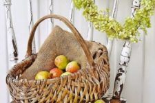 18 a harvest themed fall display with a greenery wreath and a basket with burlap and apples
