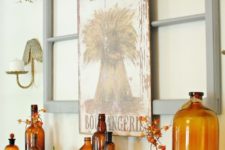 24 a bright fall mantel with amber bottles, berries and white pumpkins, a sign and some branches