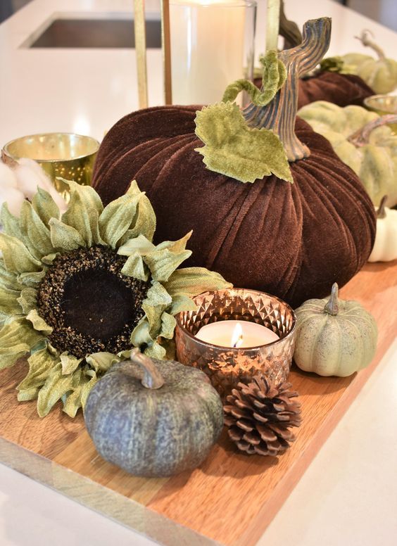 a simple rustic fall display with a wooden board, pinecones, faux pumpkins and blooms plus candles