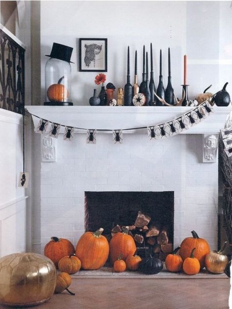 a Halloween mantel and a fireplace with orange pumpkins, black and orange candles and a pumpkin in a cloche