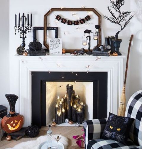 a bold Halloween mantel with black candles, lights, a black tree, glam embellished pumpkins and a bunting