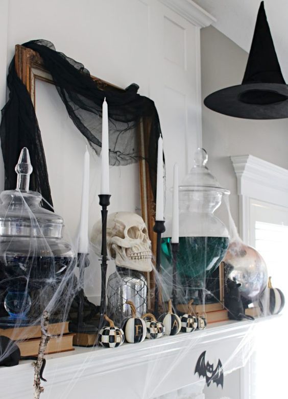 a bold Halloween mantel with black tille, a witch hat, black and white oumpkins and witches' brew in jars