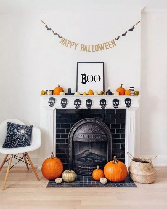 a bright mantel with orange and gold pumpkins, a skull bunting, candles and a sign plus a bat bunting over the mantel