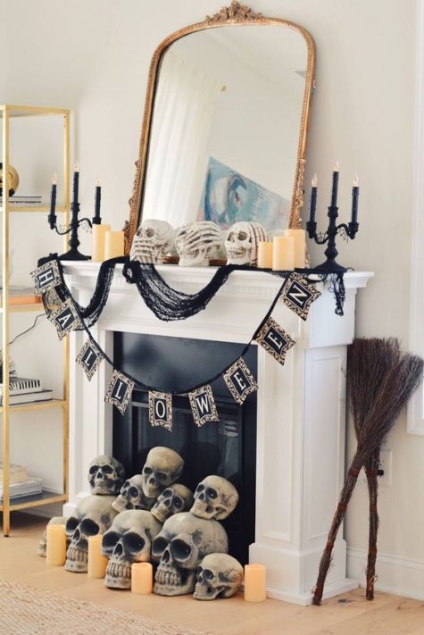 a glam Halloween mantel with a large mirror, black candleholders, a bunting and lots of skulls