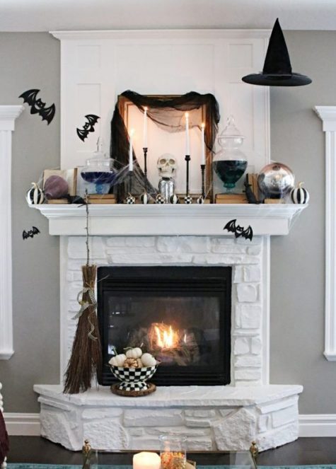 a spooky Halloween mantel with checked pumpkins, candles, dark tulle, bats and some witches’ brew