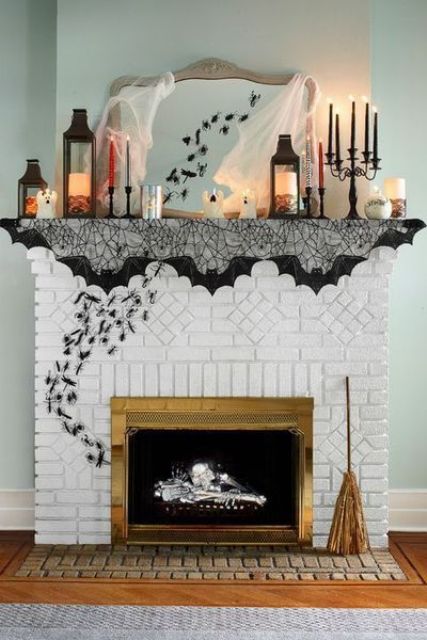 a stylish and simple Halloween mantel with psiders, a black spiderweb cover, candle lanterns, black candles and tulle