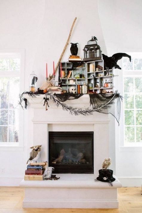 a whimsical Halloween mantel with blackbirds and owls, stacks of books, black tulle and candles