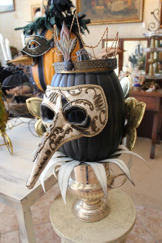 a cool matte black pumpkin in a crown and a mask is a gorgeous decoration or Halloween centerpiece
