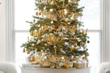 11 a tabletop Christmas tree with white and lots of gold ornaments and a large star topper for a festive feel