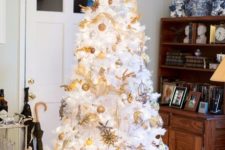 13 a white Christmas tree with lots of gold ornaments and ribbons plus a gold topper looks magical and bold